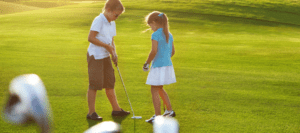 Two young kids (a boy and a girl) playing golf.